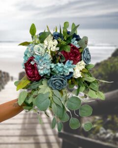 blues and vintage white silk flowers with a pop of maroon and green for a bridal bouquet