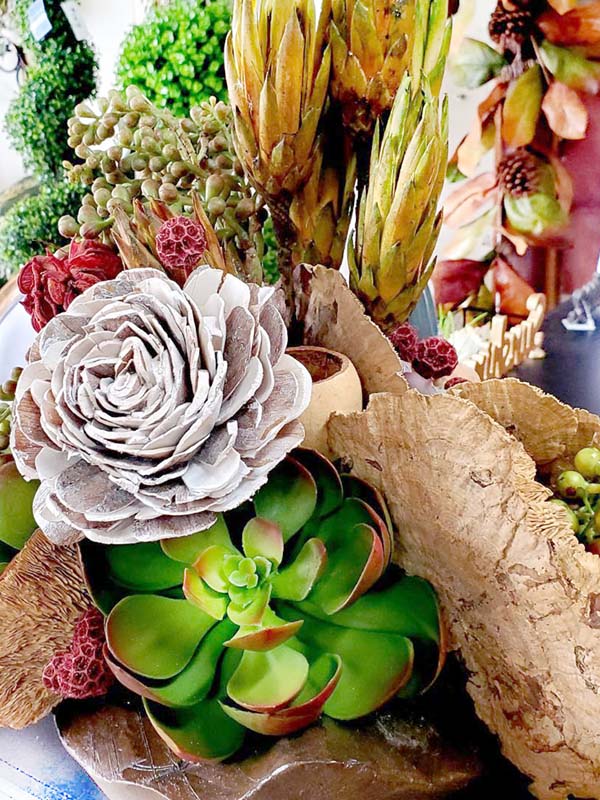 artificial flowers and green succulents arrangement on a side board