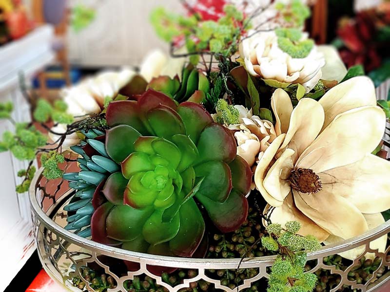 green and cream colored artificial succulents in a decorative metal tray