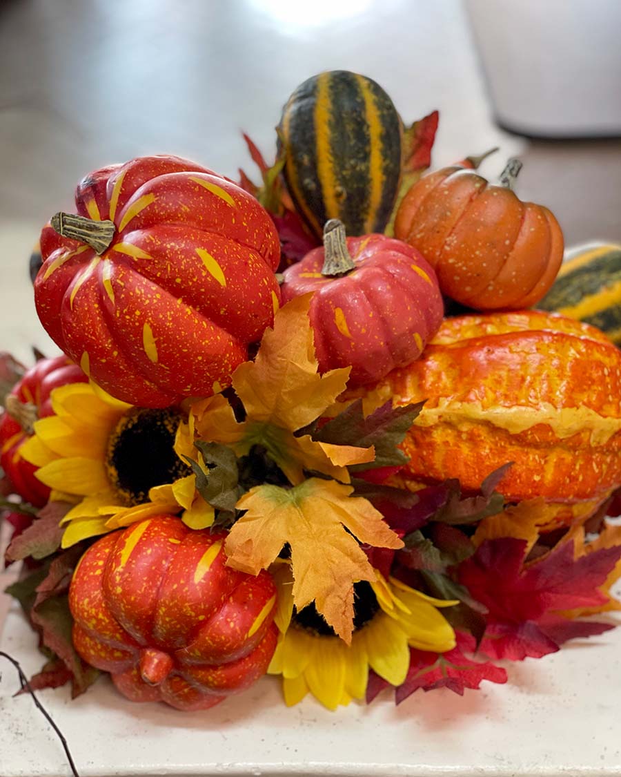 Artificial arraignment of fall colored leaves and pumpkins