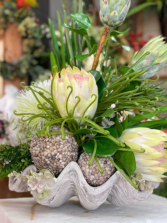 Silk flowers in whites with green spray in a shell bowl